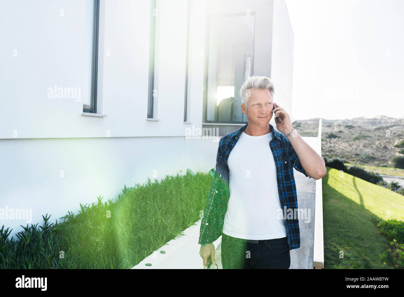Legerer Mann außerhalb seines modernen Home Unterhaltung am Telefon Stockfoto