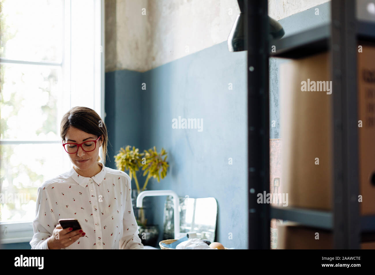 Frau mit Smartphone im Büro kitchenet Stockfoto