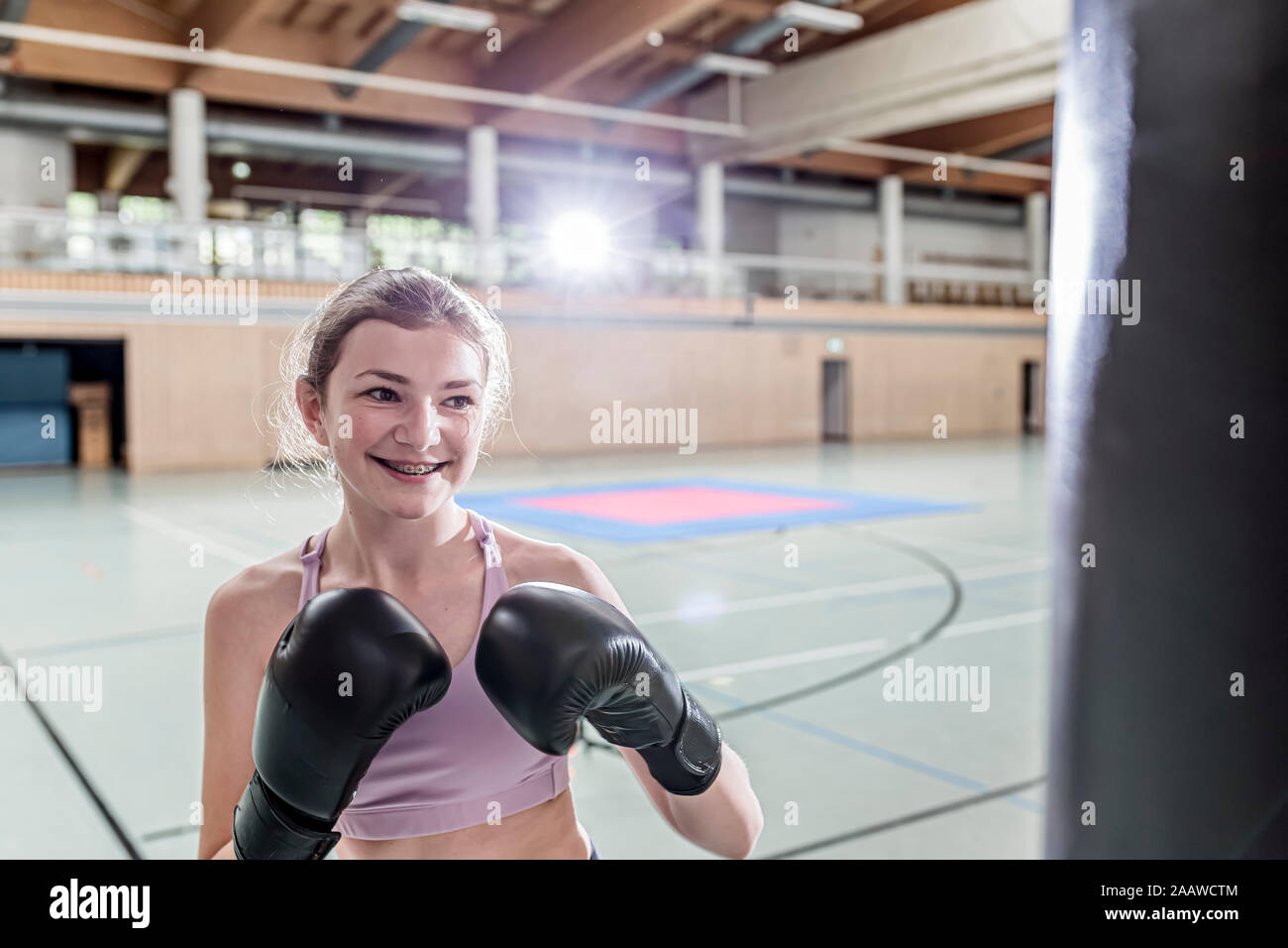 Lächelnd weibliche Boxer üben an Boxsack in der Sporthalle Stockfoto