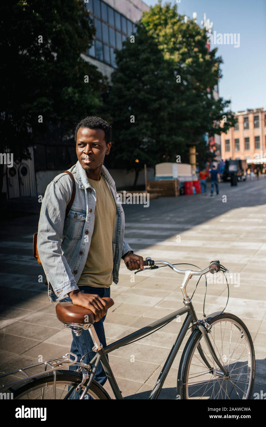 Commuiting zoung Mann in der Stadt, sein Fahrrad schieben Stockfoto