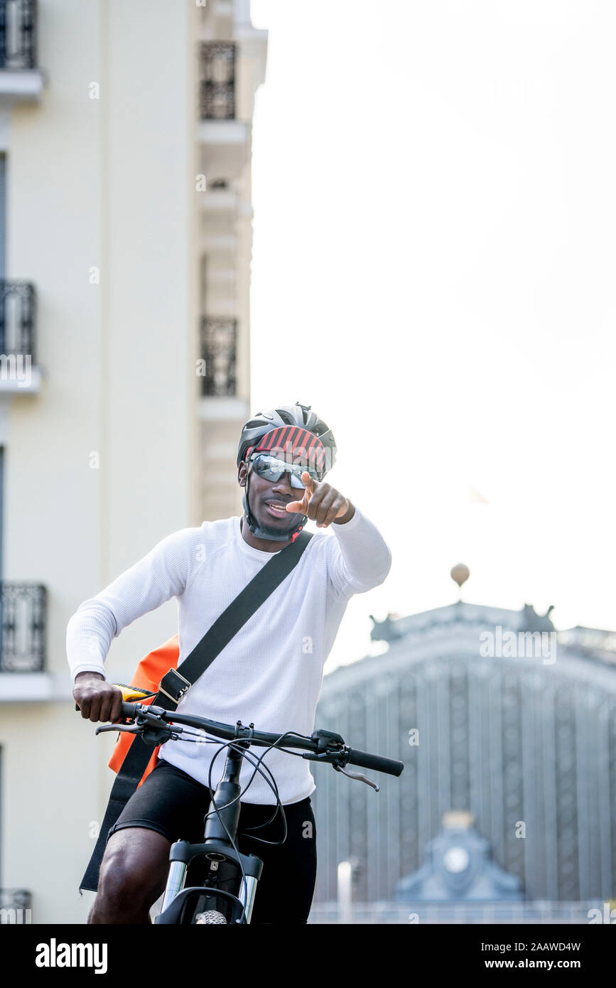 Stilvolle Junger Mann mit Fahrrad und Messenger Bag in der Stadt seinen Finger Stockfoto