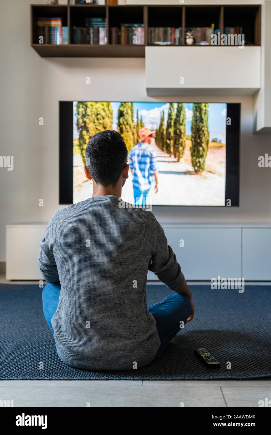 Rückansicht des Menschen sitzen auf dem Boden zu Hause Fernsehen Stockfoto