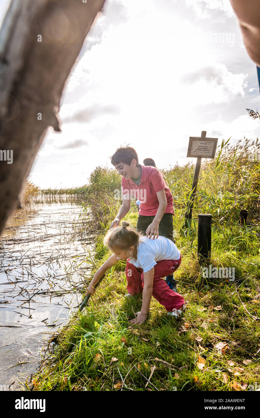 Kinder spielen mit Holz Stick am Gewässer, Darß, Mecklenburg-Vorpommern, Deutschland Stockfoto