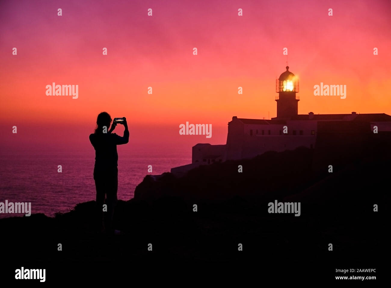 Portugal, Algarve, Silhouette der Person, smart phone Fotos von Kap St. Vincent Leuchtturm in der Dämmerung Stockfoto