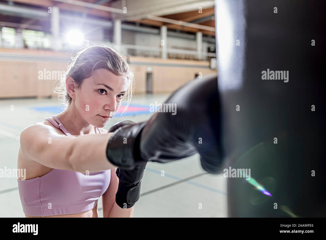 Weibliche Boxer üben an Boxsack in der Sporthalle Stockfoto