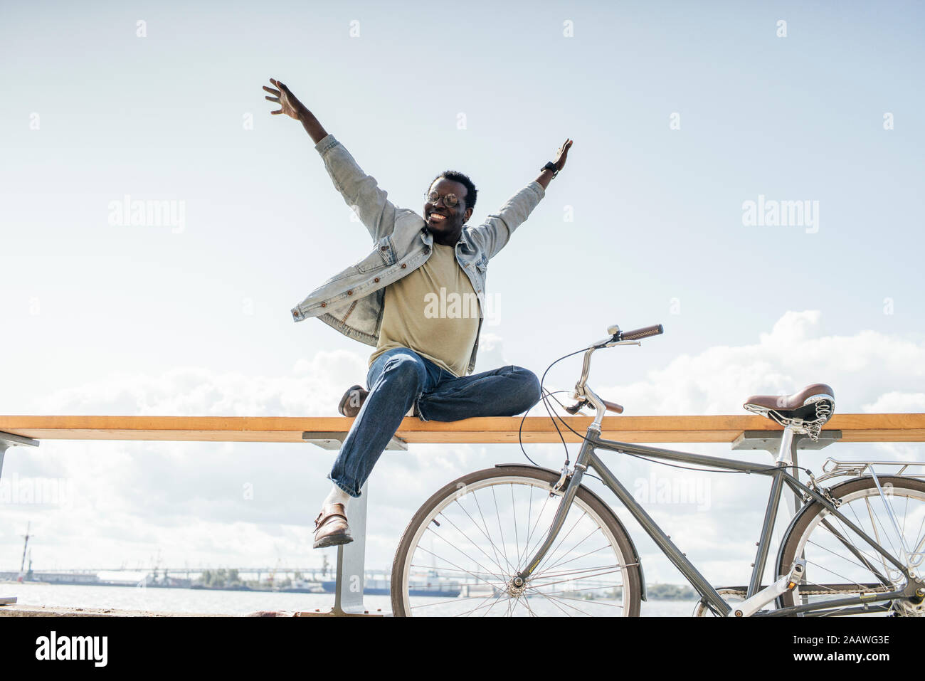 Junger Mann mit Fahrrad, sitzen auf railng durch das Meer, das so tut, als zu fliegen Stockfoto