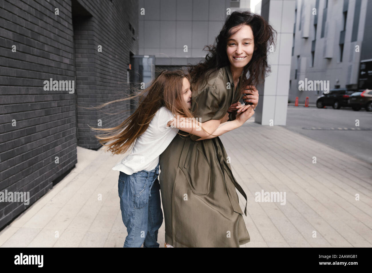 Mädchen umarmte ihre lächelnde Mutter Stockfoto