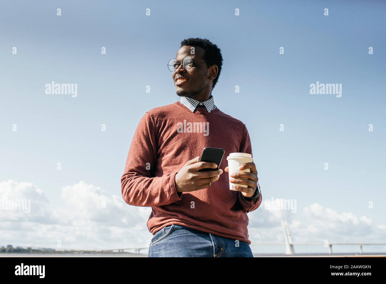 Junge Mann am Meer, Kaffee, halten Sie Ihr Smartphone Stockfoto