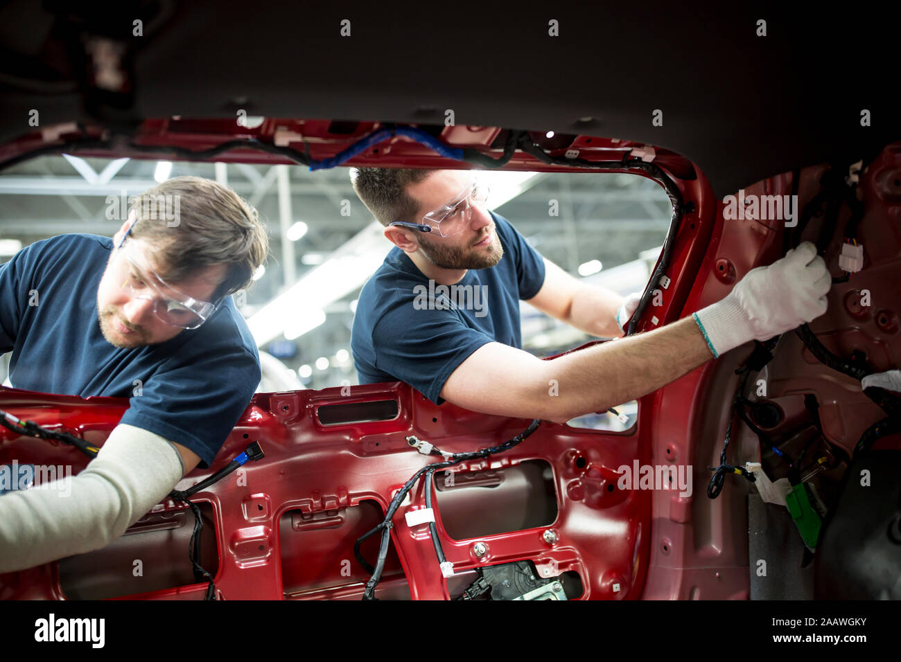 Zwei Kollegen an der Karosserie in der modernen Autofabrik arbeiten Stockfoto