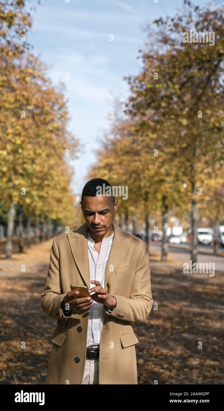 Portrait von Geschäftsmann mit Smartphone im Herbst Stockfoto