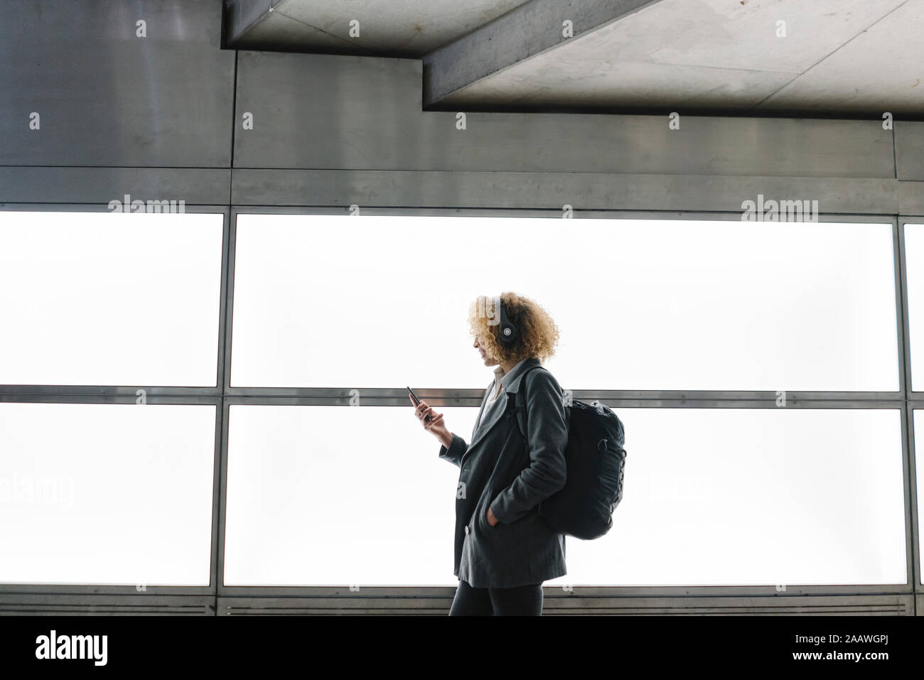 Frau mit Kopfhörer und Rucksack mit Smartphone Stockfoto