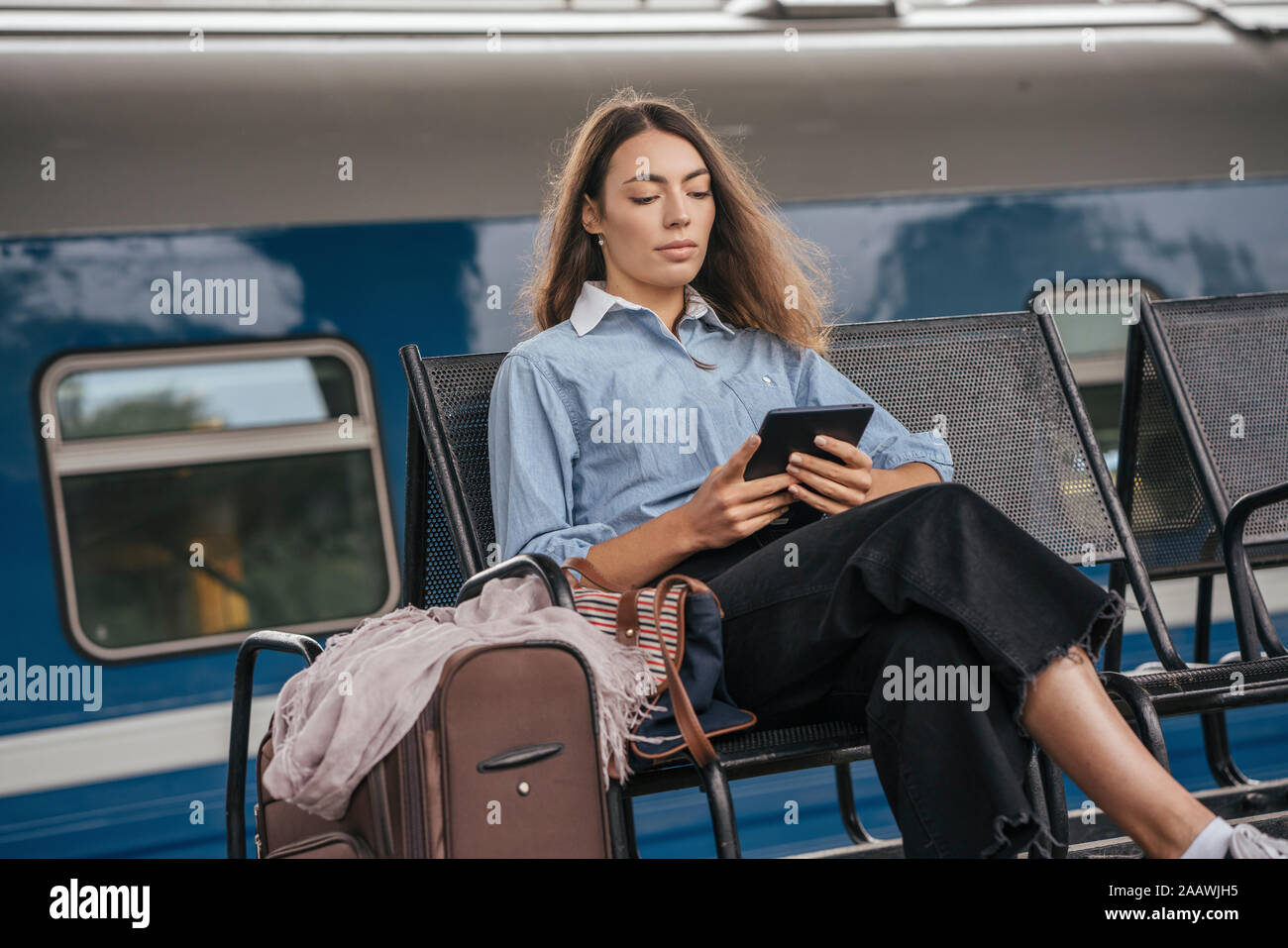Junge weibliche Reisende warten auf Station, mit e-book Stockfoto