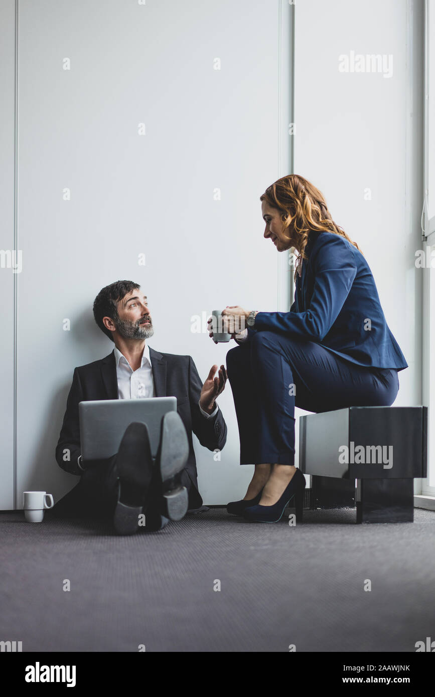 Mit Geschäftsmann im Büro sitzen auf dem Boden mit Laptop Geschäftsfrau Stockfoto