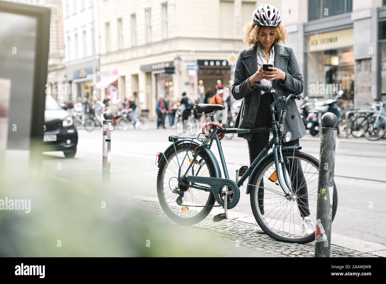Frau mit Fahrrad und Smartphone in der Stadt, Berlin, Deutschland Stockfoto
