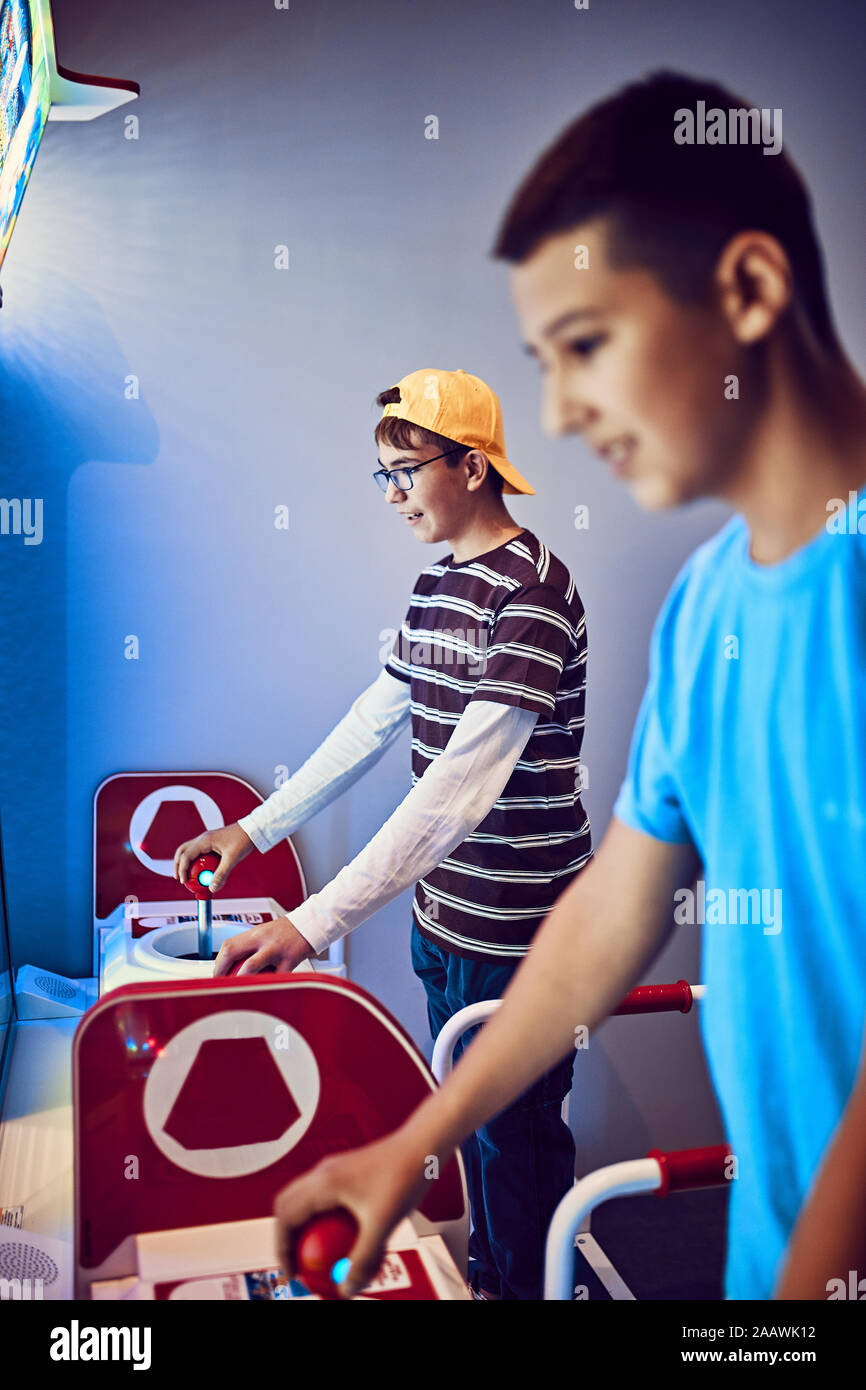 Teenage Freunde spielen Mit einem Gaming Maschine in eine Spielhalle Stockfoto