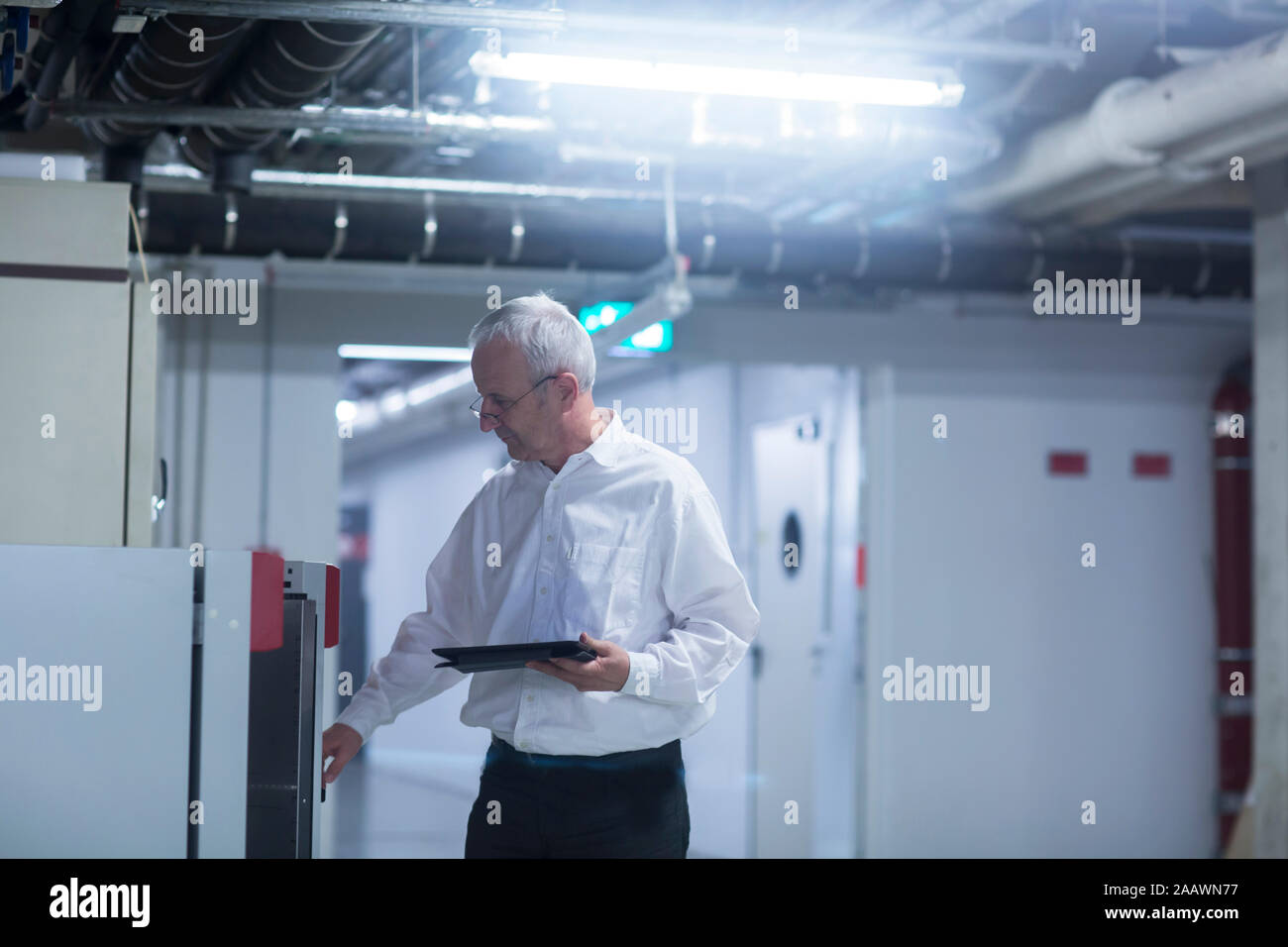 Älterer Mann an der Maschine in der Fabrik arbeiten, bei Tablet suchen Stockfoto