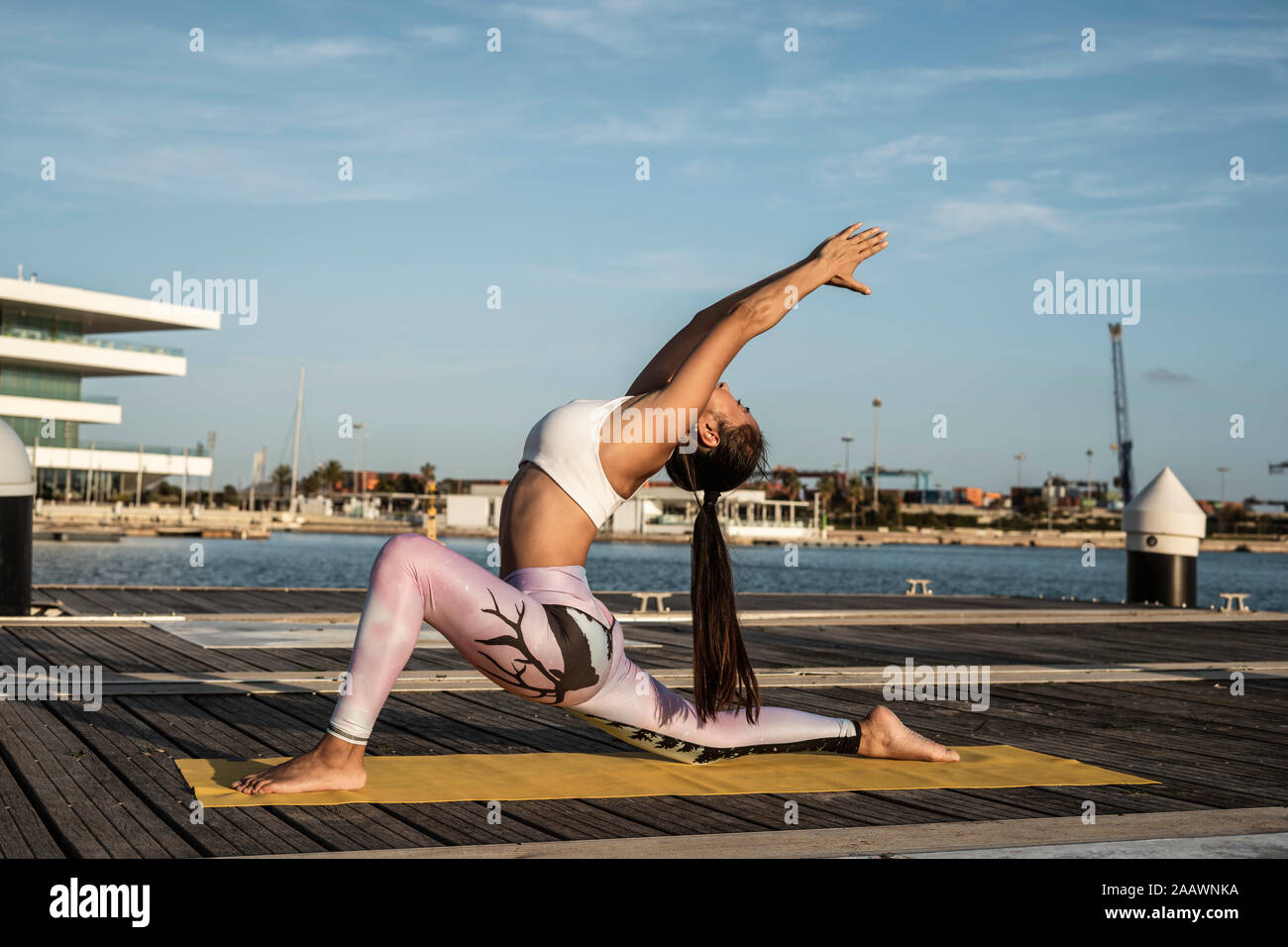Asiatische frau yoga auf einem Pier am Hafen, Krieger darstellen Stockfoto