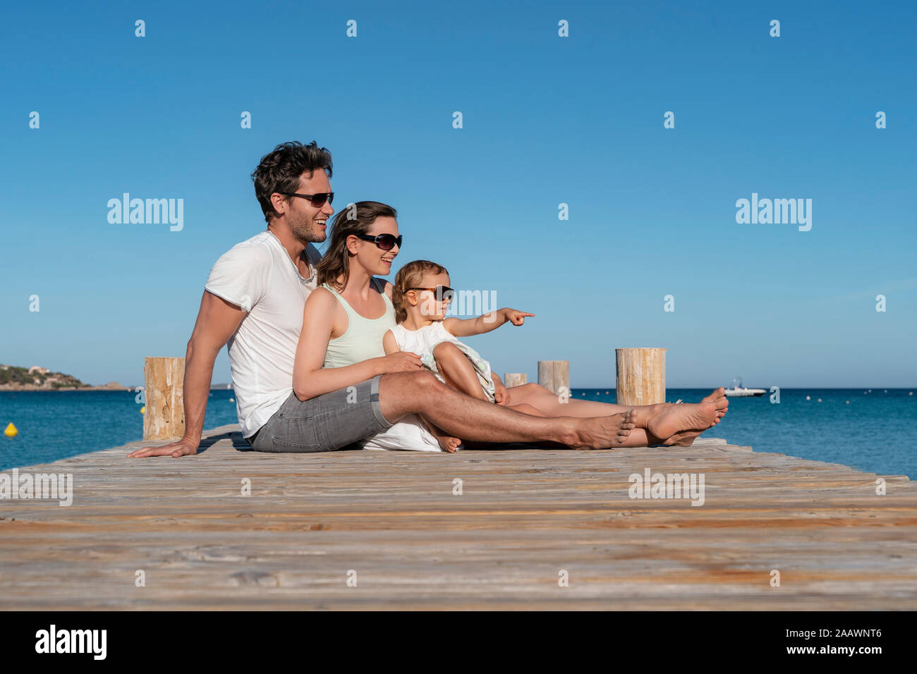 Glückliche Familie sitzt auf einem Steg am Meer Stockfoto