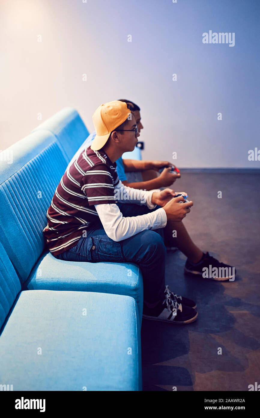 Teenage Freunde spielen video game in eine Spielhalle Stockfoto