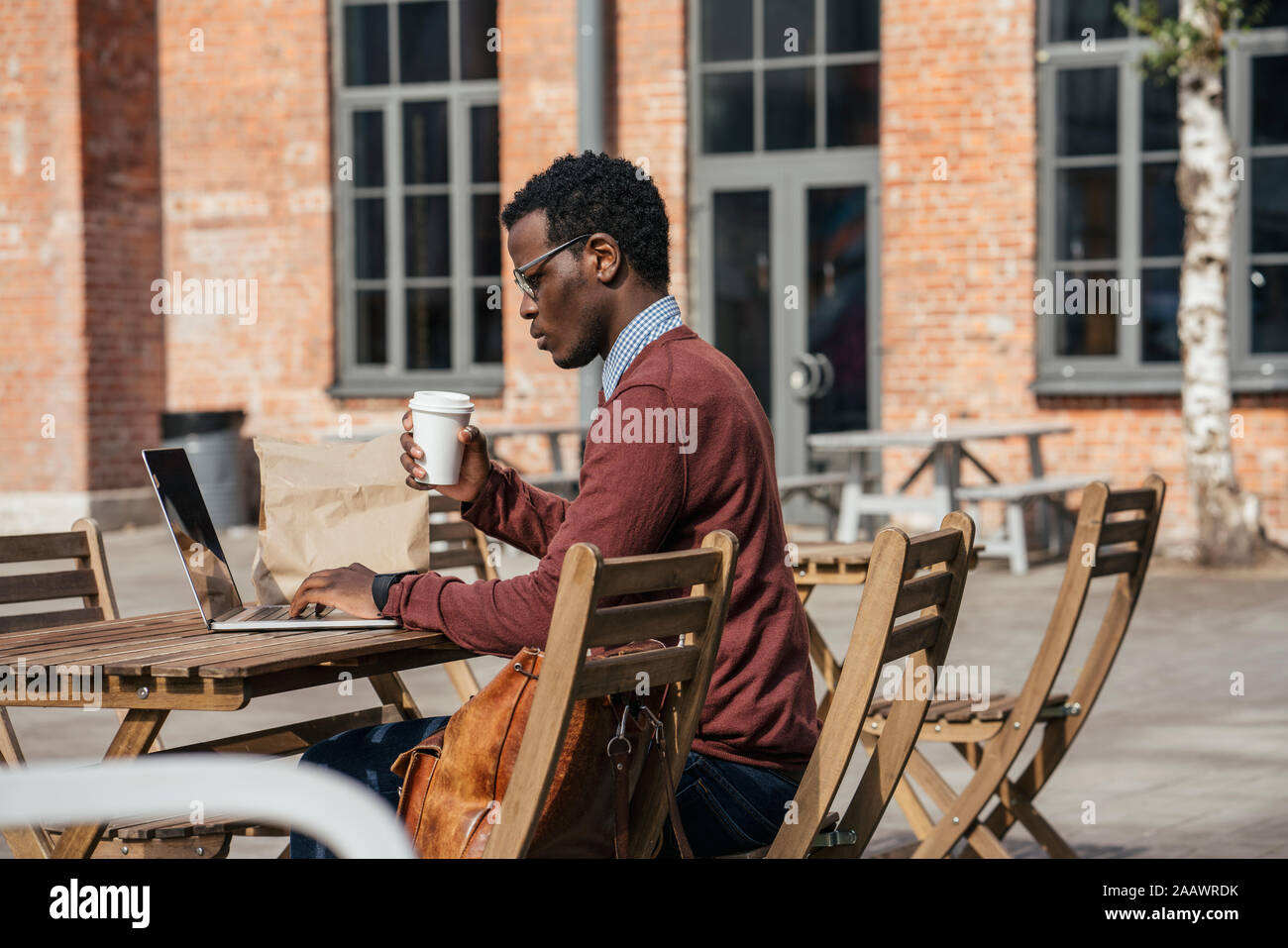 Junger Mann mit Laptop im Coffeeshop, Kaffee trinken Stockfoto