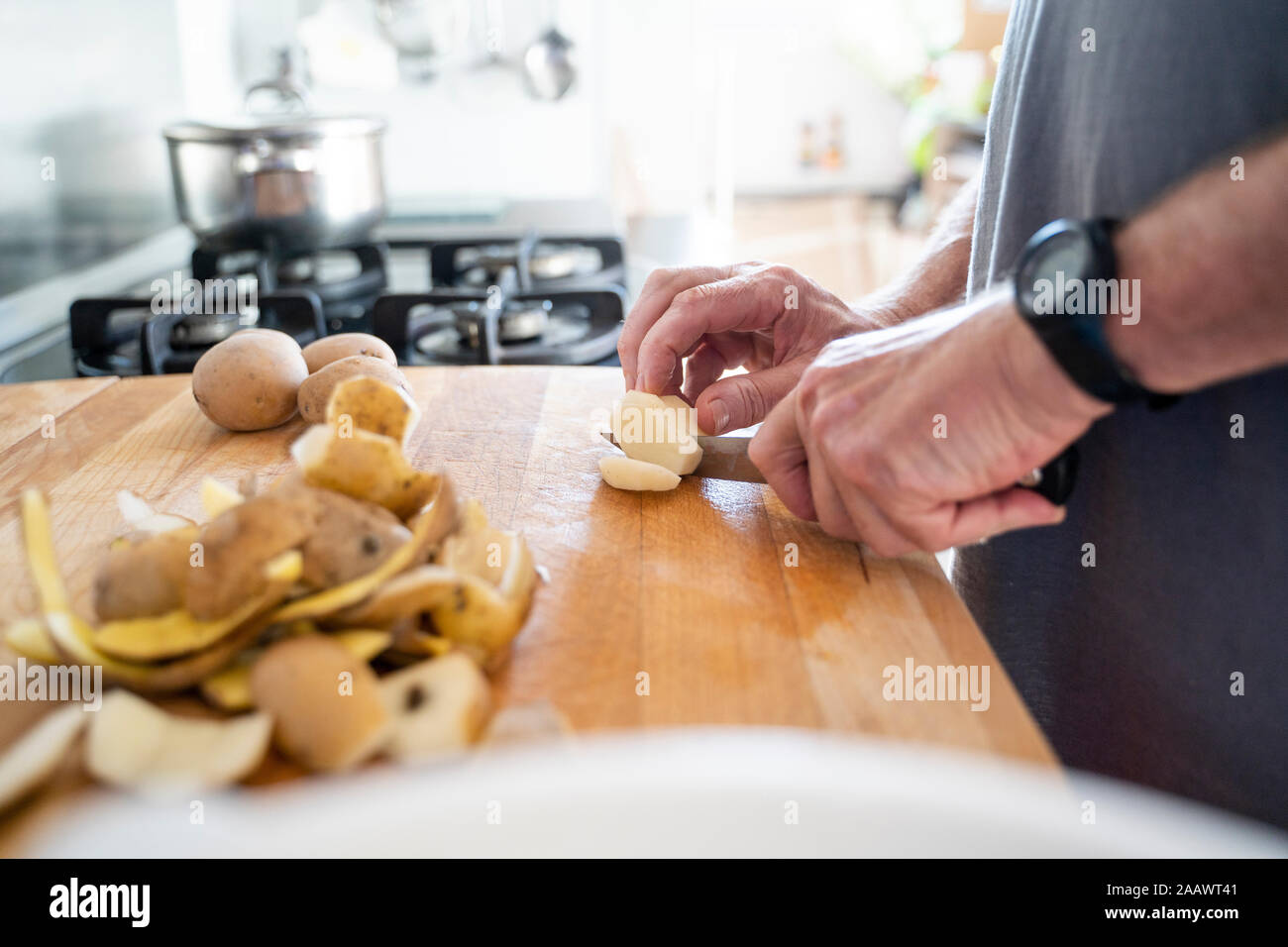 Ältere Menschen schneiden Kartoffeln auf dem Schneidebrett Stockfoto
