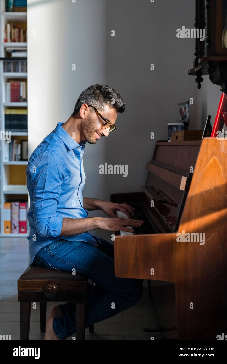 Portrait von lächelnden jungen Mann spielt Klavier zu Hause Stockfoto
