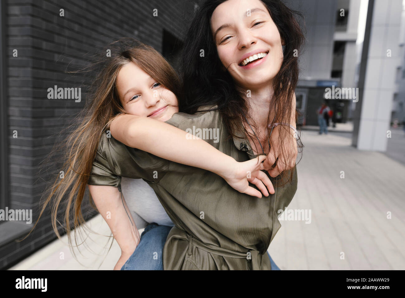 Portrait der glücklichen Mutter, die ihre Tochter ein piggyback Ride Stockfoto