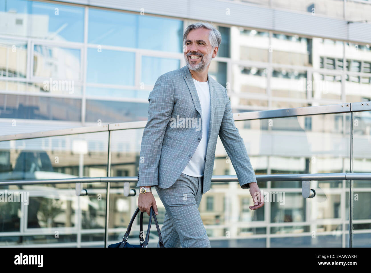 Lächelnd Modische Reifen Geschäftsmann mit Tasche für unterwegs Stockfoto