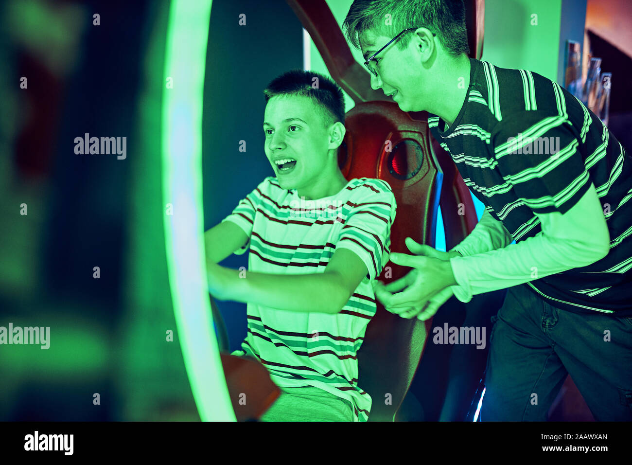 Teenage Freunde spielen und Spaß mit einem Fahrsimulator in eine Spielhalle Stockfoto