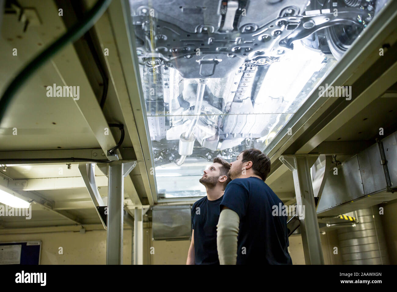 Zwei Kollegen im Werk überprüfen Unterboden des Autos Stockfoto