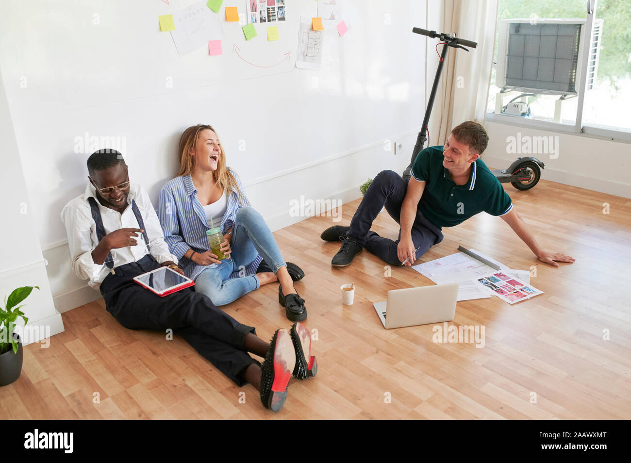 Glückliche junge Geschäftsleute sitzen zusammen in einem Büro in einem informellen Treffen Stockfoto