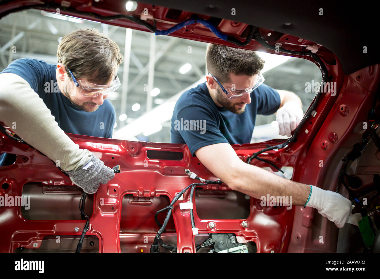 Zwei Kollegen an der Karosserie in der modernen Autofabrik arbeiten Stockfoto