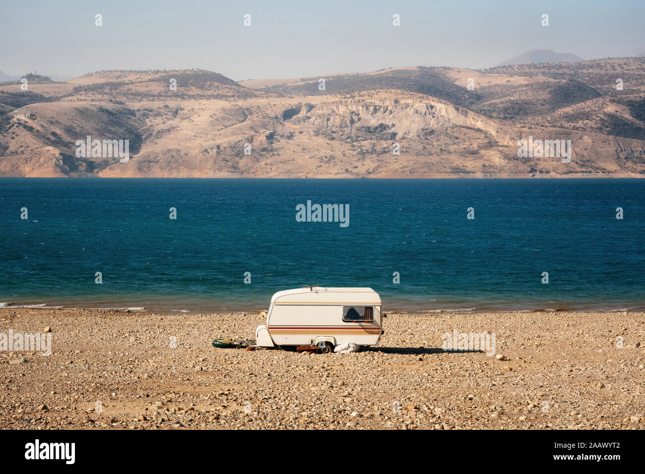 Ein einsamer Wohnwagen am Ufer des Sees zwischen Wüste und Berge geparkt, Usbekistan Stockfoto