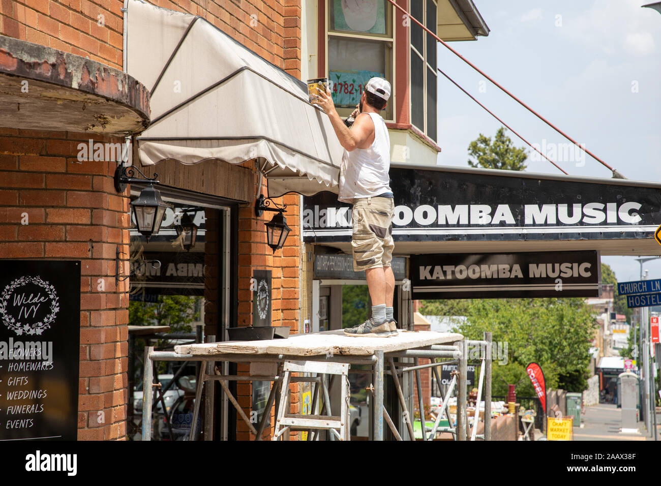 Mann, der als Maler in Katoomba Blue Mountains NSW arbeitet Warten auf ein Geschäft Markise auf prekären Gerüst Stockfoto