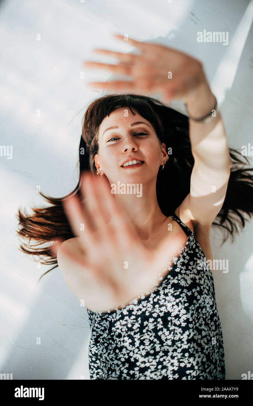 Schöne brünette Frau auf dem Boden liegend, Lachen und bewegliche Arme Stockfoto