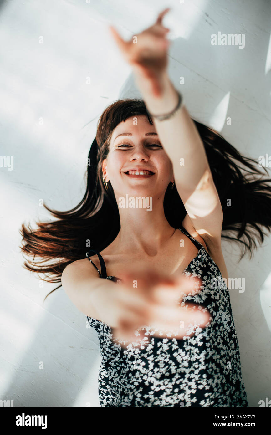 Sorglos brünette Frau auf dem Boden liegend, Lachen und bewegliche Arme Stockfoto