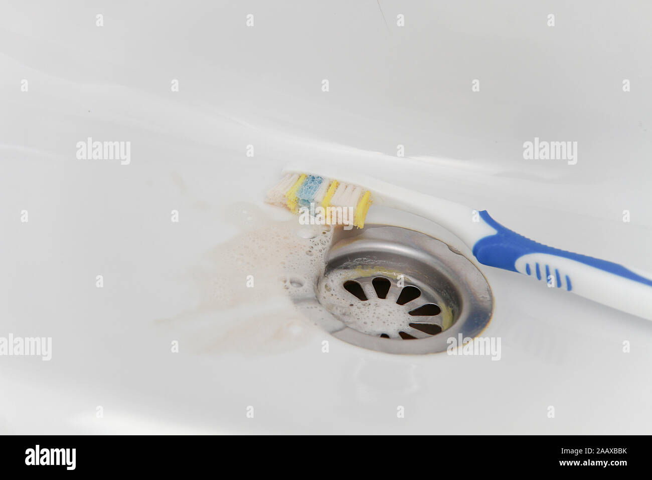 Blut und Zahnpasta auf der Zahnbürste nach dem Reinigen und Waschen der Zahnbürste. Schmerzkonzept und Gesundheit Stockfoto