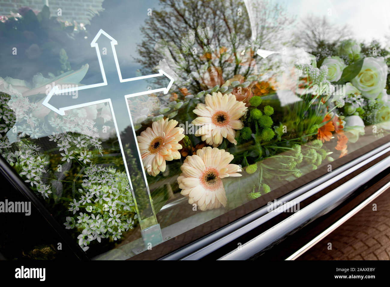 Schwarzer Leichenwagen mit einem Kranz von Blumen und eine Religion Kreuz bereit zum Begräbnis zu gehen Stockfoto