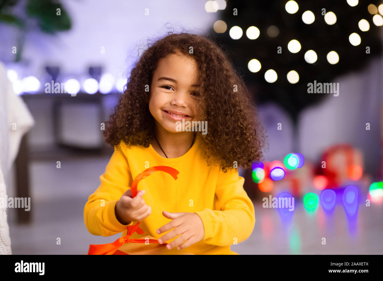 Cute afrikanisches Mädchen öffnen Weihnachtsgeschenk zu Hause Stockfoto