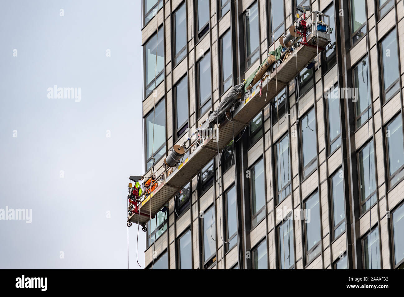 Hohes Arbeiter. Ein Wartung Arbeiter auf einer Hubarbeitsbühne hoch oben auf dem Gesicht von einem Bürogebäude in Philadelphia. Stockfoto