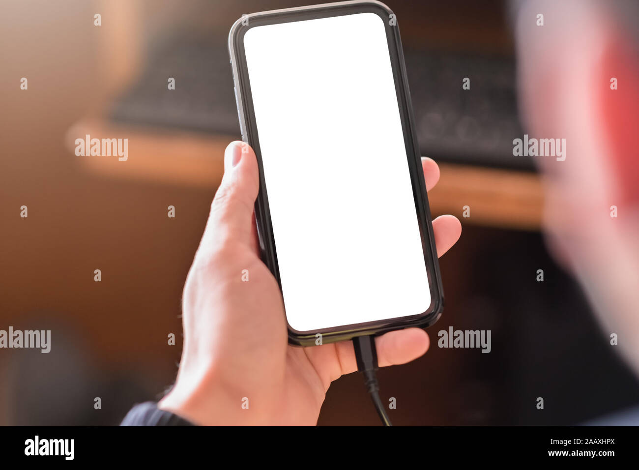 Mann hand Smartphone und Gerät und Aufladen des Geräts während der Verwendung mit leeren weißen Bildschirm für mockup Stockfoto