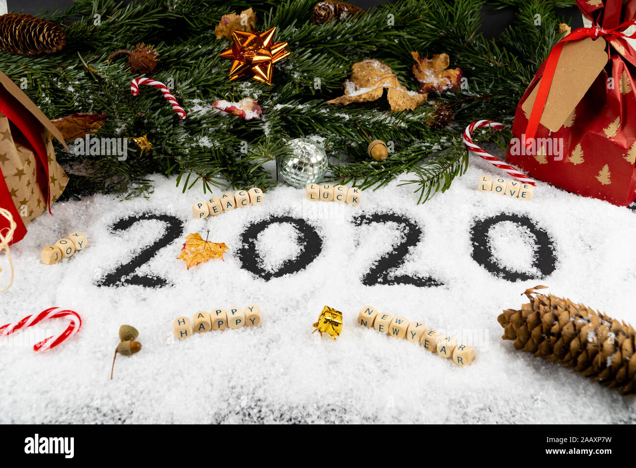 Eine Anordnung mit '2020' im Schnee in der vorderen geschrieben, gute Wünsche, wie Frieden, Glück, Liebe, Freude und einen guten Rutsch ins neue Jahr. Die Rückseite ist eingerichtet w Stockfoto