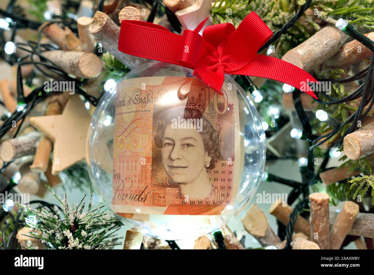 Zehn Pfund Hinweis in einer klaren Weihnachtskugel auf einen Baum. Stockfoto