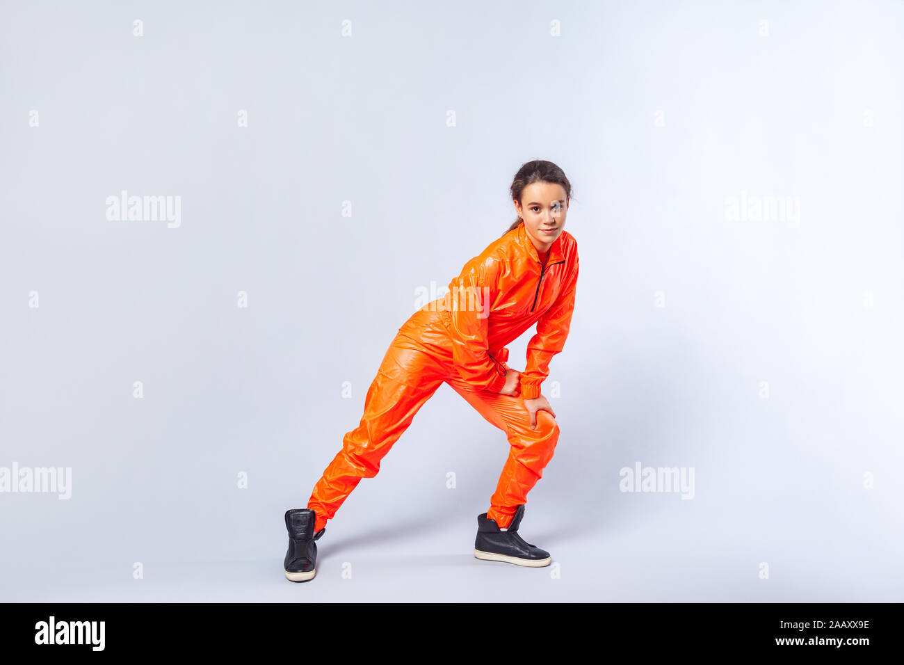 Volle Länge Bild der energetischen Jugendmädchen mit Brünette Haar helle orange Overall tanzen, mit Schmetterling hip hop bewegen, Hobby activitie Stockfoto