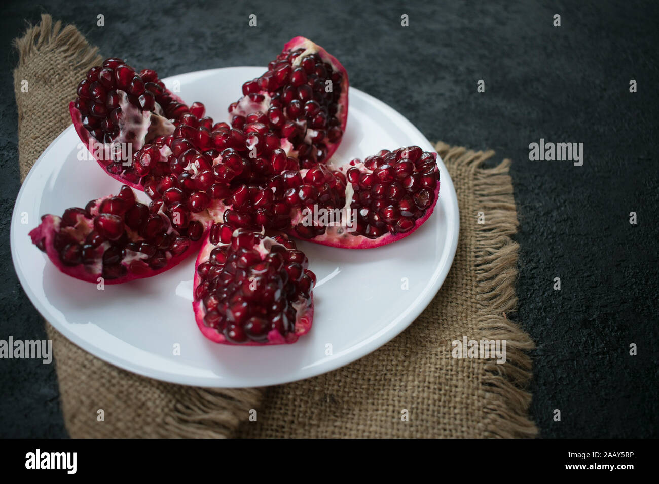 In einer weißen Platte Granatapfel auf schwarzem Hintergrund. Stockfoto