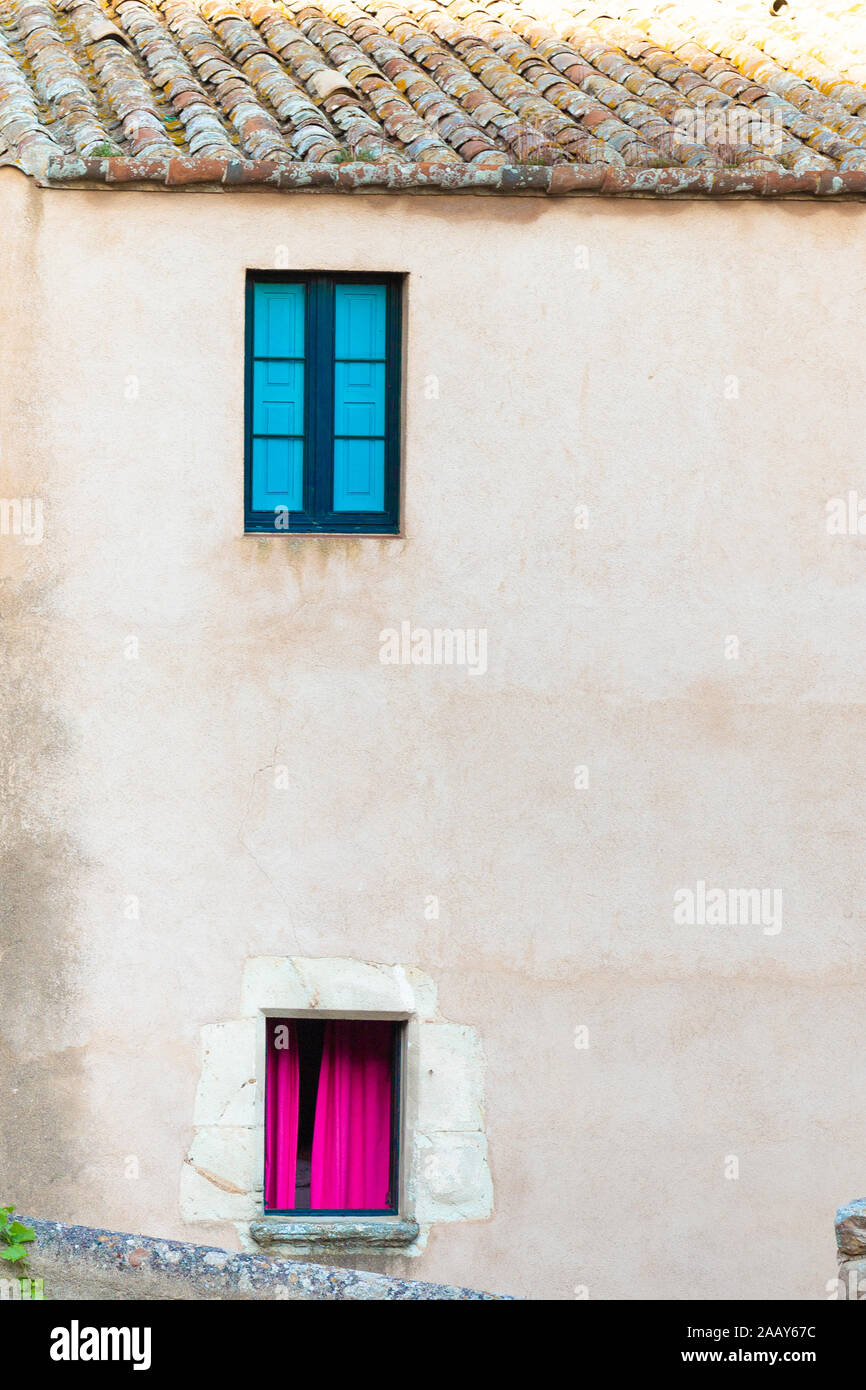 Zwei farbige Fenster an der Steinmauer eines alten Hauses. Stockfoto