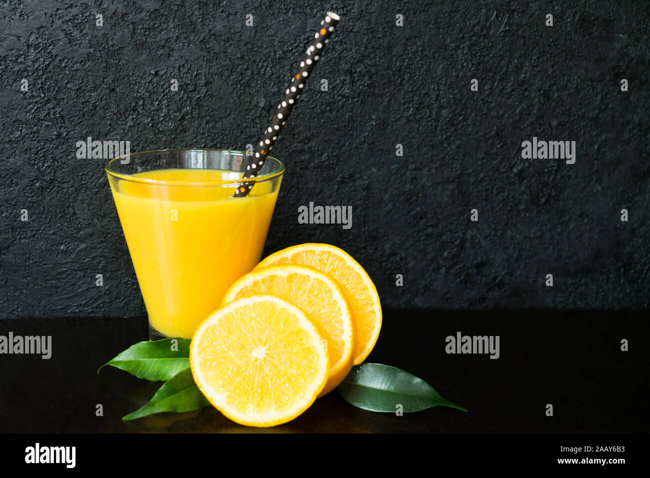 Glas orange und Orangenscheiben auf schwarzem Hintergrund. Stockfoto