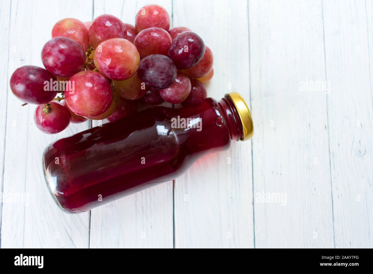 Traubensaft in einer Flasche auf einem weißen Holz- Hintergrund. Stockfoto