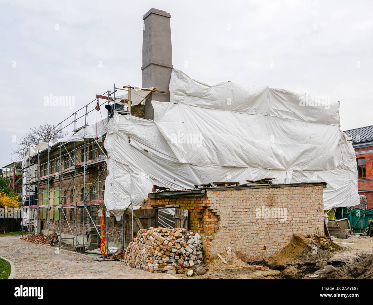 Wiederaufbau eines alten zweistöckigen Backsteinhaus, Fassade mit grünen Netz abgedeckt Stockfoto