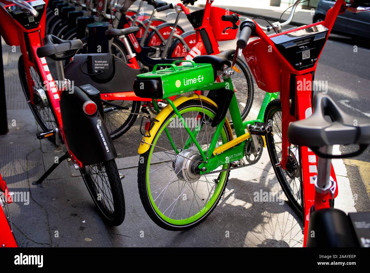 Eine Kalk-E und Springen elektrische Hilfe Zyklus Sharing Station mit Fahrrädern, in der mit den lebendigen Farben, die sich in den frühen Morgen Sonne abgestellt Stockfoto